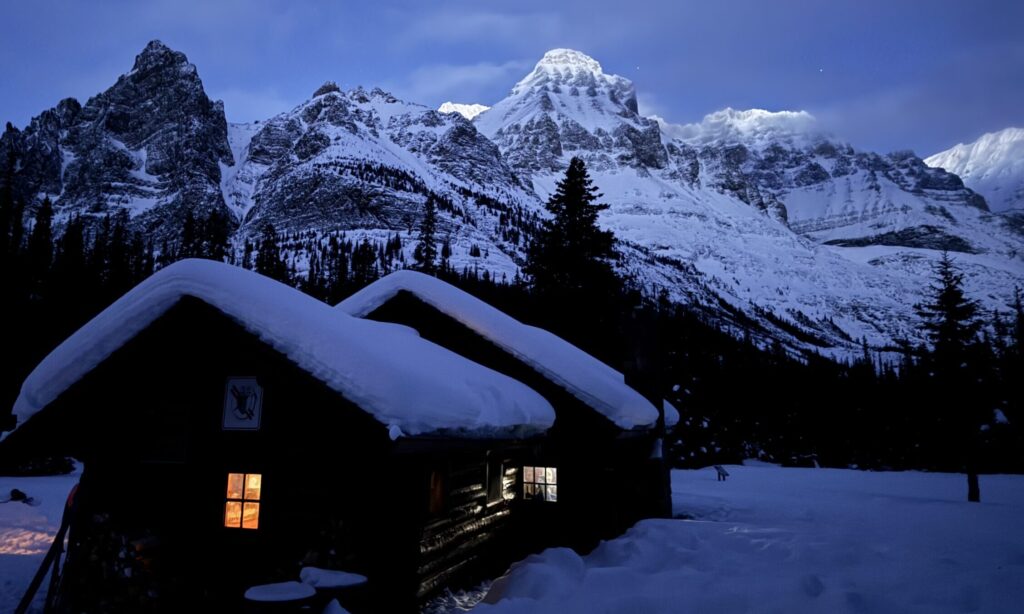 Image of a ski hut in the winter night, with bright lights on