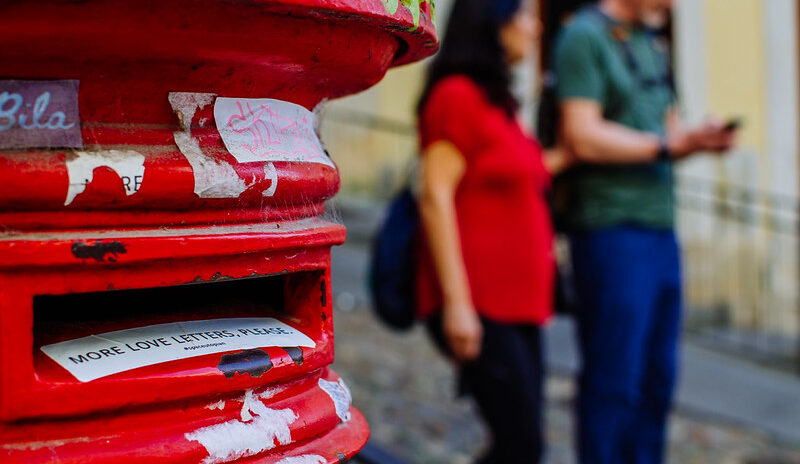 Image of two people standing beside a postbox